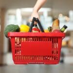 Woman,holding,shopping,basket,with,different,food,products,at,supermarket,