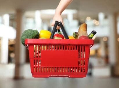 Woman,holding,shopping,basket,with,different,food,products,at,supermarket,