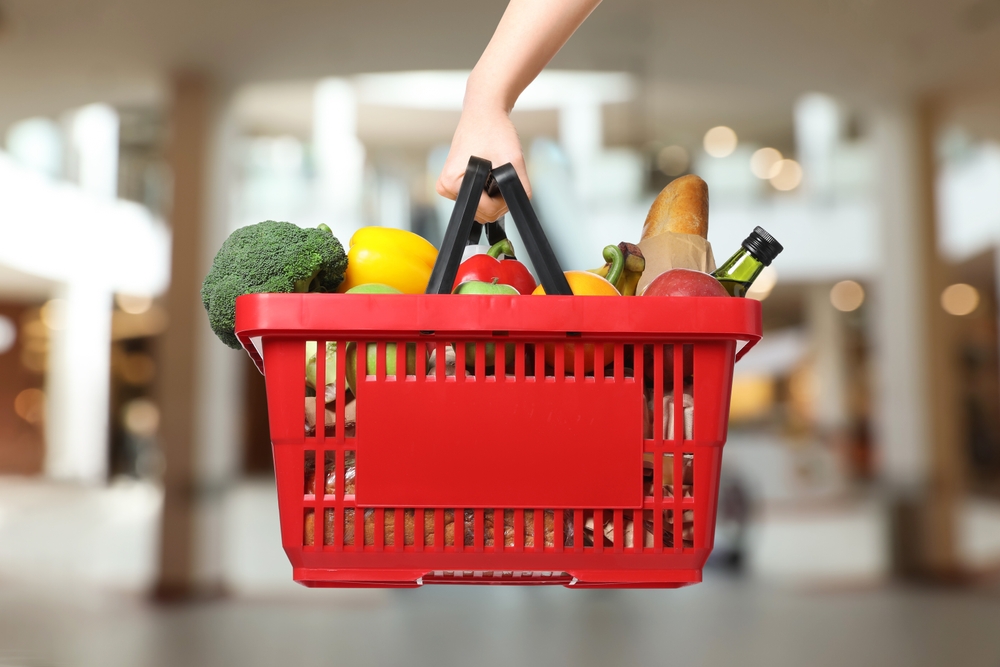 Woman,holding,shopping,basket,with,different,food,products,at,supermarket,