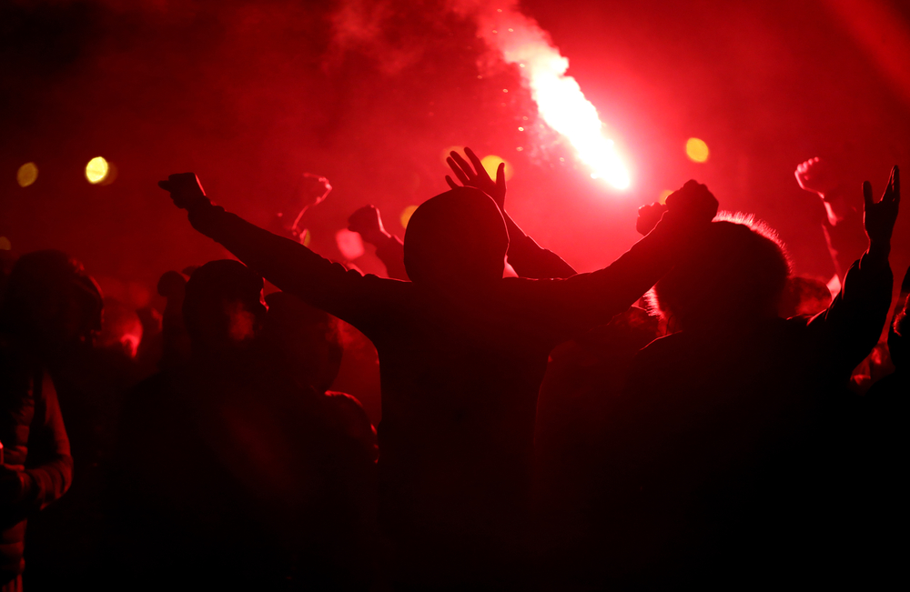 Football,fans,cheer,with,lighted,torches,during,the,match