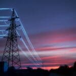 Electric,transmission,towers,with,glowing,wires,against,the,sunset,sky