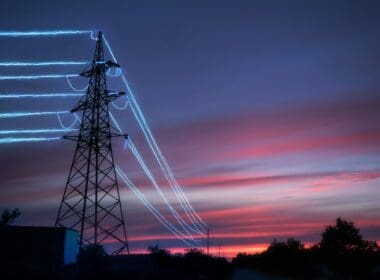 Electric,transmission,towers,with,glowing,wires,against,the,sunset,sky