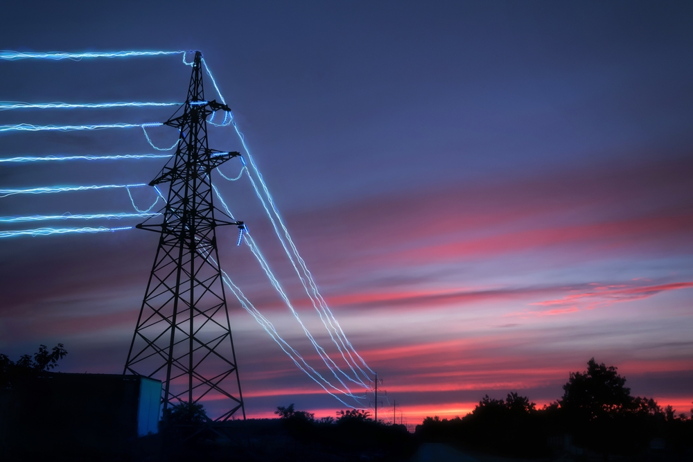 Electric,transmission,towers,with,glowing,wires,against,the,sunset,sky