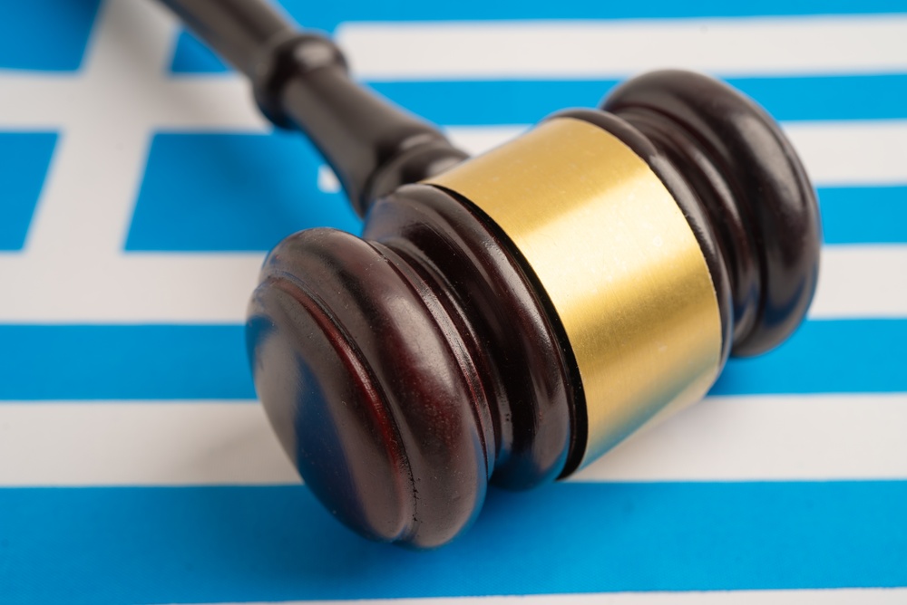 Greece,legal,,justice,and,agreement,,wooden,court,gavel,on,flag
