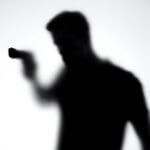 Shadow,of,male,killer,aiming,gun,through,glass,wall,,contract