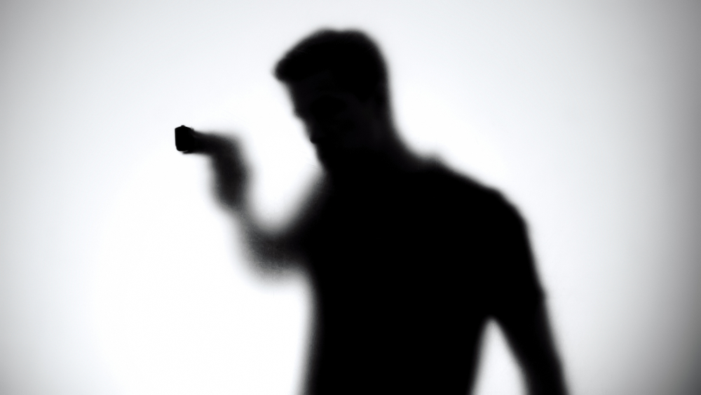 Shadow,of,male,killer,aiming,gun,through,glass,wall,,contract